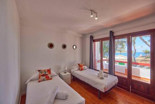 two beds in a room with a view of the ocean at Nura Houses Duplex Magaluf 1 in Magaluf
