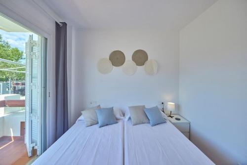 ein weißes Schlafzimmer mit einem großen Bett mit blauen Kissen in der Unterkunft Nura Houses Apatment Magaluf 4 in Magaluf