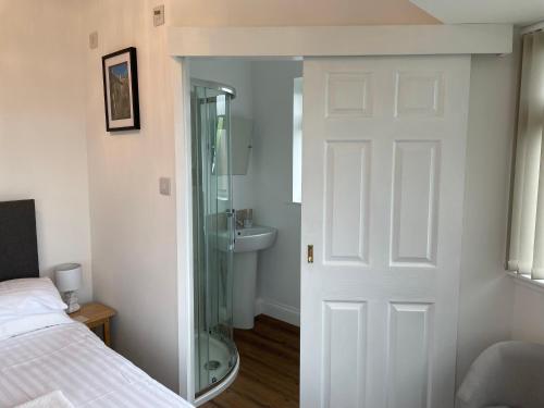 a bedroom with a glass door leading to a bathroom at The Mandalay Guest House in Mevagissey