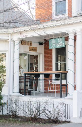 a cafe with a table in the front of a building at Auberge de Jeunesse Magog-Orford Hostel in Magog-Orford