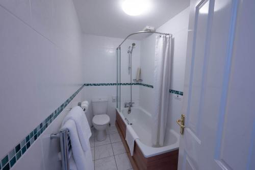 a bathroom with a tub and a toilet and a shower at Tregarthen's Hotel in Hugh Town