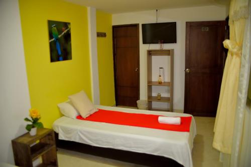 a bedroom with a bed with a red blanket at Hotel Casa Alejandria in Quimbaya