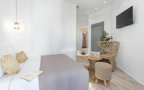 a white bedroom with a bed and a chair and a laptop at Majestique of Naxos boutique hotel in Naxos Chora