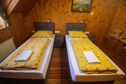 two beds in a room with wooden walls at Radics Panzió Étterem és Pihenő Központ in Letenye
