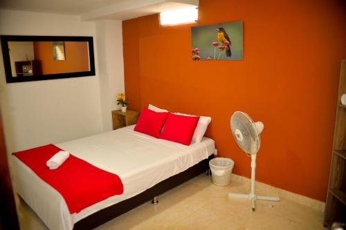 キンバヤにあるHotel Casa Alejandriaのベッドルーム1室(赤い枕とファン付きのベッド1台付)