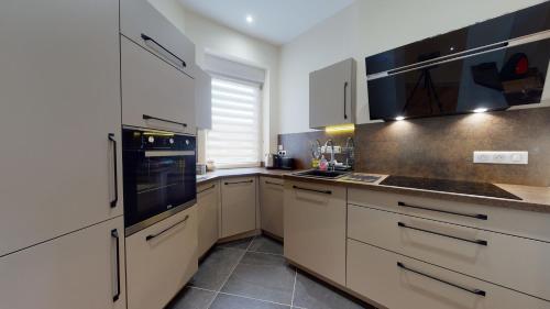 une cuisine avec des armoires blanches et un appareil noir dans l'établissement Le Muguet 3 chambres - 1 GARAGE GRATUIT, à Colmar