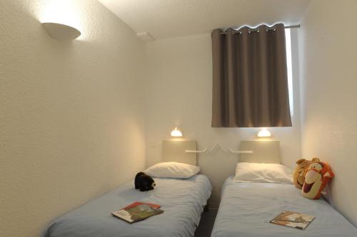 Cette chambre dispose de 2 lits avec un ours en peluche et un chat. dans l'établissement ULVF les Ramondies, à Saint-Lary-Soulan