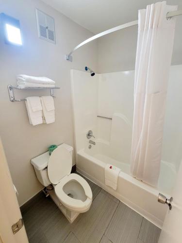 a white bathroom with a toilet and a bath tub at Super 8 by Wyndham Marion NC in Marion