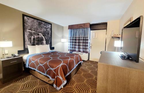 una camera d'albergo con un letto e una TV a schermo piatto di Super 8 by Wyndham Marion NC a Marion