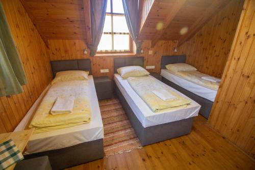three beds in a room with wooden walls at Radics Panzió Étterem és Pihenő Központ in Letenye