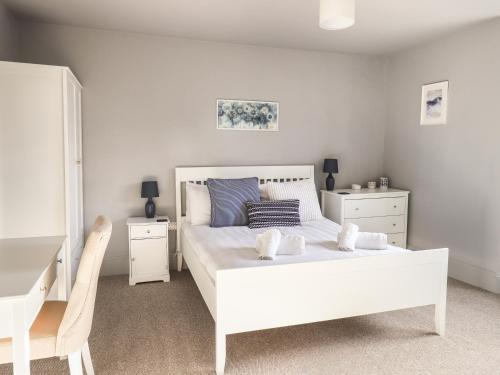 een witte slaapkamer met een wit bed en een stoel bij Raybarrow in Windermere