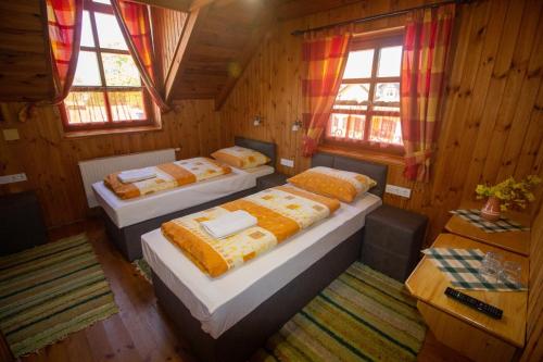 three beds in a room with wooden walls and windows at Radics Panzió Étterem és Pihenő Központ in Letenye