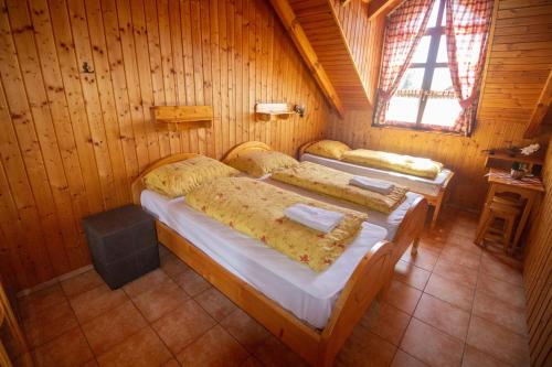 two beds in a wooden room with a window at Radics Panzió Étterem és Pihenő Központ in Letenye