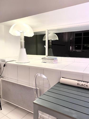 une table blanche avec deux lumières et un miroir dans l'établissement ÉLÉGANT STUDIO et PARKING DANS BATIMENT HISTORIQUE, à Saint-Tropez