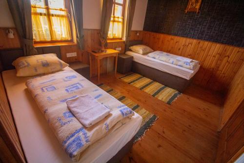 two beds in a room with wooden floors and windows at Radics Panzió Étterem és Pihenő Központ in Letenye