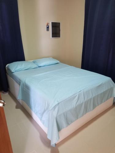 een bed met blauwe lakens en blauwe gordijnen in een kamer bij The View Apartment in Willemstad