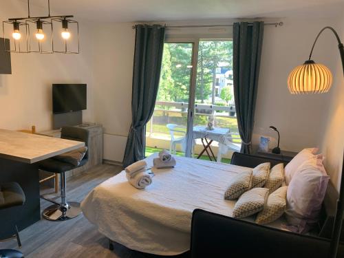 Un dormitorio con una cama y una mesa y una ventana. en Studio les mélèzes vue montagne Barcelonnette, en Barcelonnette