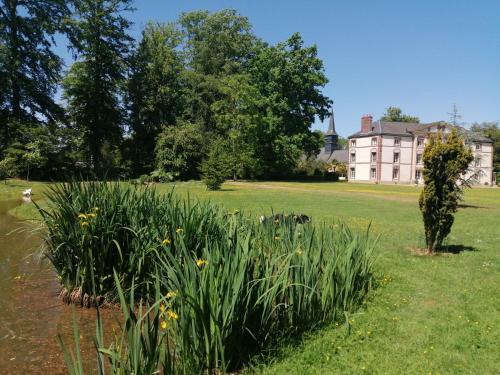 un campo de hierba con una casa en el fondo en Chambre Le Notre Le Domaine Des Jardins De Bracquetuit, en Bracquetuit