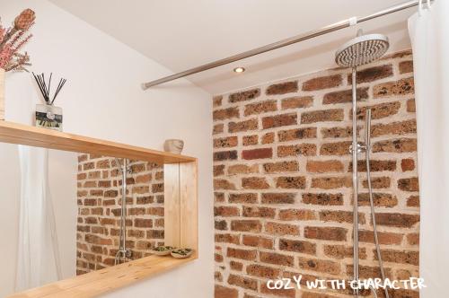 een badkamer met een bakstenen muur en een douche bij Cozy with Character Vibrant Cottage Style Flat at Leith Links Park in Edinburgh