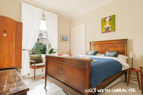 a bedroom with a bed and a chair and a window at Cozy with Character Vibrant Cottage Style Flat at Leith Links Park in Edinburgh