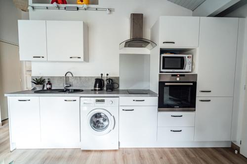 a kitchen with white cabinets and a washer and dryer at LA FORESTIERE - Petit havre de paix au Pyla, face aux pins in La Teste-de-Buch