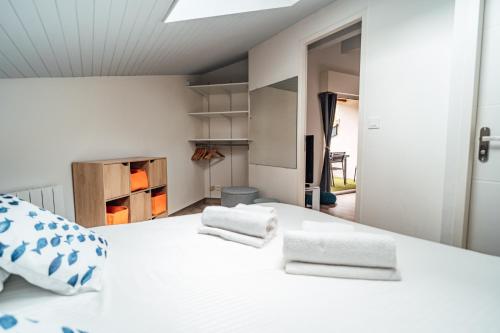 a bedroom with a white bed with two towels on it at LA FORESTIERE - Petit havre de paix au Pyla, face aux pins in La Teste-de-Buch