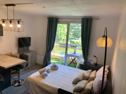 Un dormitorio con una cama y una mesa y una ventana. en Studio les mélèzes vue montagne Barcelonnette, en Barcelonnette