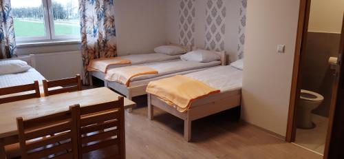 Habitación pequeña con 2 camas y mesa. en Noclegi nad Biebrzą Stara Szkoła, en Wroceń