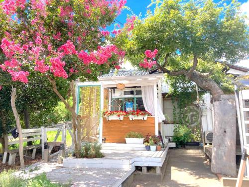 une maison avec un arbre planté de fleurs roses dans l'établissement NEMARU Live with Books, à Nagaoka