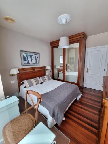 a bedroom with a large bed and a mirror at Piso de 3 habitaciones a 3 minutos de la playa. in Ribeira