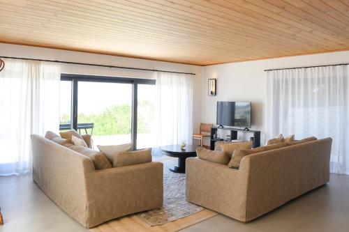 a living room with two couches and a television at Vila Luxo da Praia in Casal da Lagoa Seca