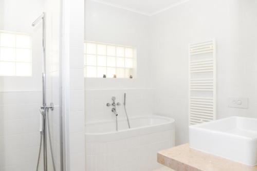 a white bathroom with a tub and a sink at Vila Luxo da Praia in Casal da Lagoa Seca