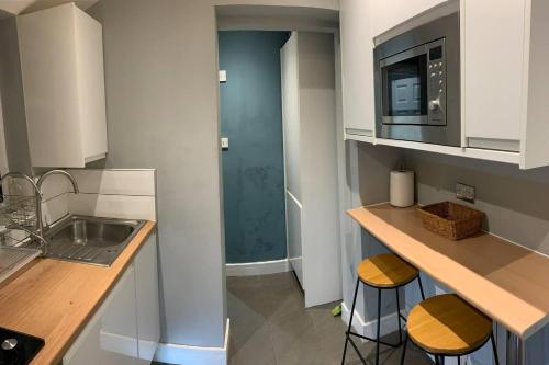 a kitchen with a sink and a counter with stools at Stunning 1-Bed Apartment in London in London