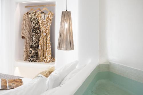a room with a bathtub and clothes hanging on a wall at Majestique of Naxos in Naxos Chora
