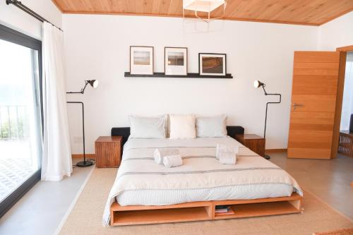 a bedroom with a large bed with white walls at Vila Luxo da Praia in Casal da Lagoa Seca