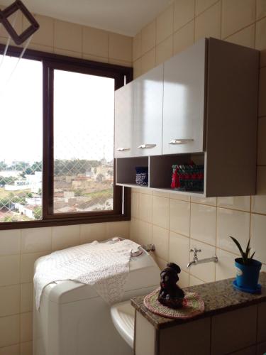 uma casa de banho com um WC, um lavatório e uma janela em Apartamento Aconchegante com Estacionamento em Uberlândia