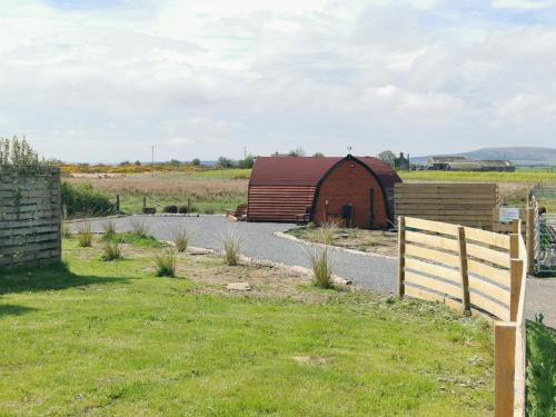 a barn in a field with a fence at Achmeney Glamping larger than Average pod in Halkirk