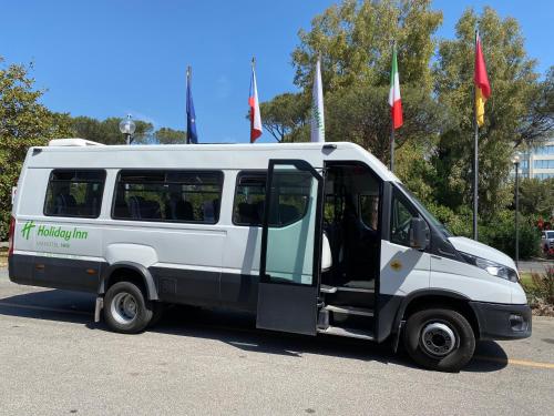 a white van parked in a parking lot with flags at Holiday Inn Rome - Eur Parco Dei Medici by IHG in Rome
