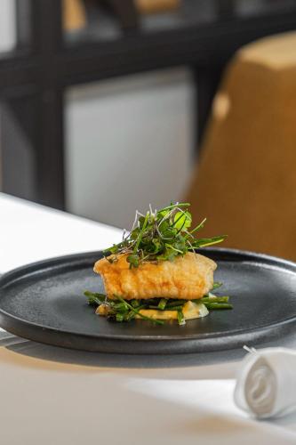 a black plate with a fish dish on a table at Terra Nostra Garden Hotel in Furnas