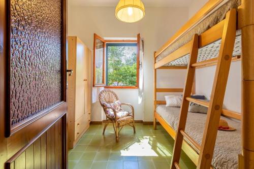 een kamer met een stapelbed, een stoel en een raam bij Villa Andrea in Codaruina