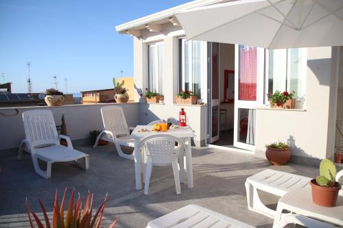 un patio con mesas y sillas blancas y una sombrilla en IL CIELO IN UNA STANZA, en Balestrate