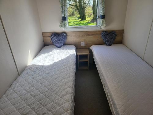 two beds in a small room with a window at Blackmoor Farm - Caravan 6 in Pembrokeshire