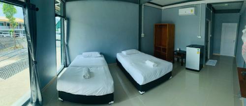 two beds in a room with a window at บ้านพิชชา ที่พักใจกลางเมืองปราณบุรี in Ban Khao Noi