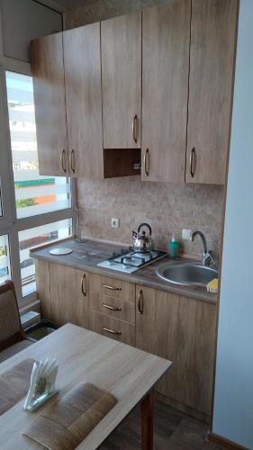 a kitchen with wooden cabinets and a sink and a table at Новобудова Центр Либiдь Плаза in Khmelʼnytsʼkyy