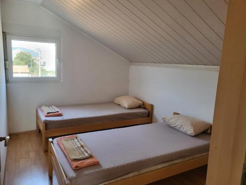 two beds in a small room with a window at Apratmani Maretic in Ugrinići