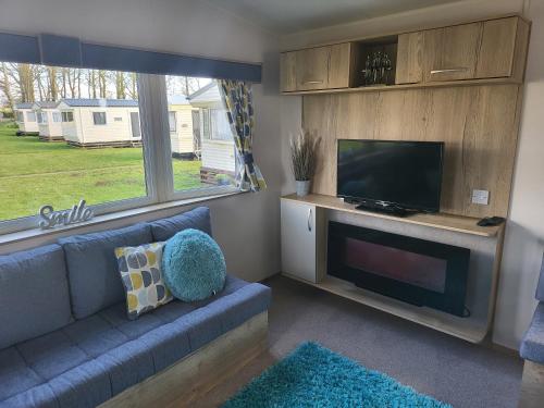 a living room with a blue couch and a flat screen tv at Blackmoor Farm - Caravan 6 in Pembrokeshire