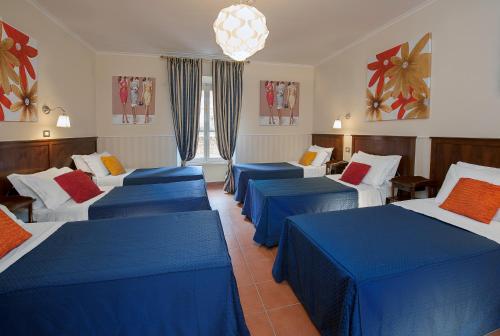 a room with four beds with blue and white sheets at Budget Rooms Des Arts in Rome