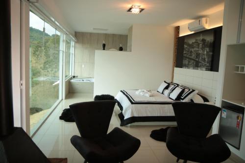 a bedroom with a bed and two chairs and a tub at Alta Vista Pousada Boutique in Córrego do Bom Jesus
