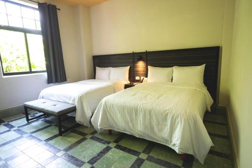a bedroom with two beds and a bench and a window at Hotel La Nacional By Kavia in Mérida