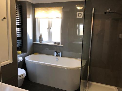 a bathroom with a tub and a toilet and a window at 9 The Coach House in Rye in Rye